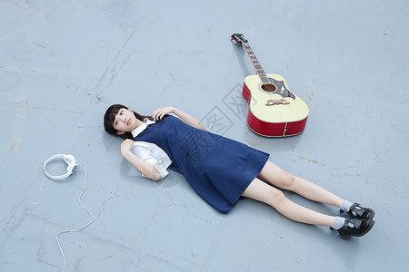 躺在天台的地上放松的高中女孩白天高清图片素材