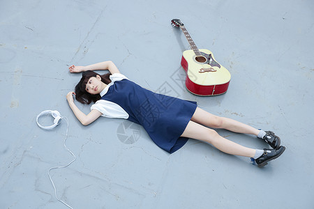躺在地上的女孩和她的吉他追赶高清图片素材
