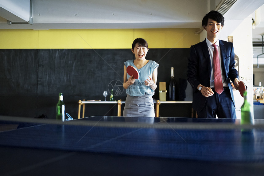 快乐的年轻商人打乒乓球的夫妇图片