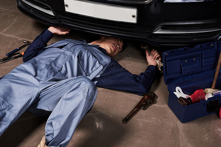 躺在地上维修汽车的维修师傅测验高清图片素材