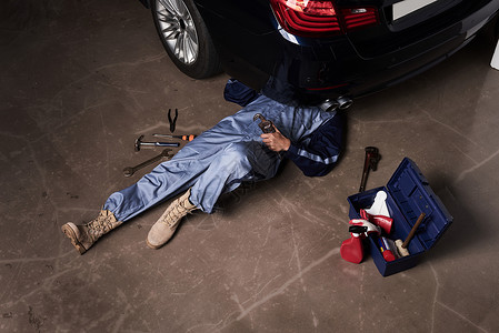 维修汽车躺在地上的汽车维修师额头高清图片素材
