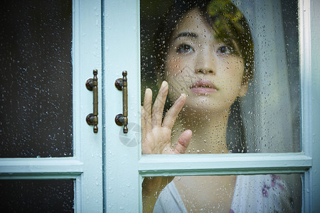 透过窗户看下雨的年轻女人古董高清图片素材