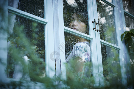 室内雨天女人在家里度过窗高清图片素材