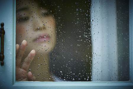 下雨天站在窗户前发呆的孤独女性房屋高清图片素材