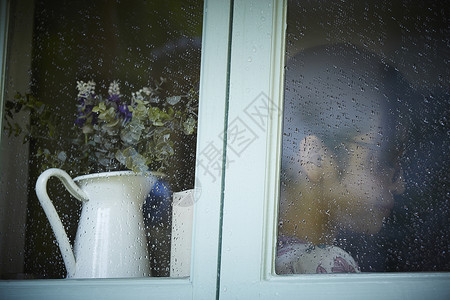 下雨天站在窗户前发呆的孤独女性背景图片