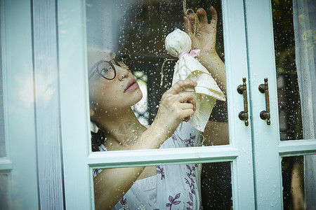 下雨天站在窗户前发呆的孤独女性咒语高清图片素材
