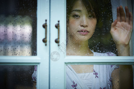 雨天女人在家里度过窗玻璃高清图片素材