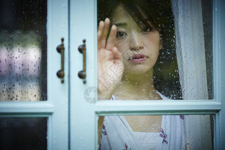 下雨天靠在窗边发呆的孤独女性女人高清图片素材