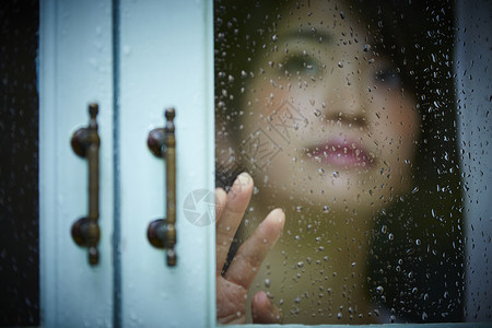 下雨天靠在窗边发呆的孤独女性房屋高清图片素材