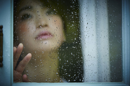 下雨天靠在窗边发呆的孤独女性暴雨高清图片素材