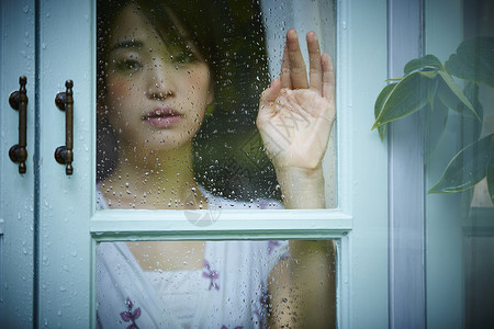 下雨天靠在窗边发呆的孤独女性度假高清图片素材