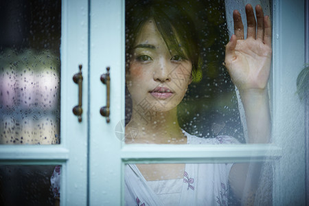 下雨天靠在窗边发呆的孤独女性暴雨高清图片素材