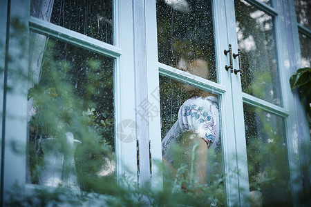 下雨天靠在窗边发呆的女性青年高清图片素材