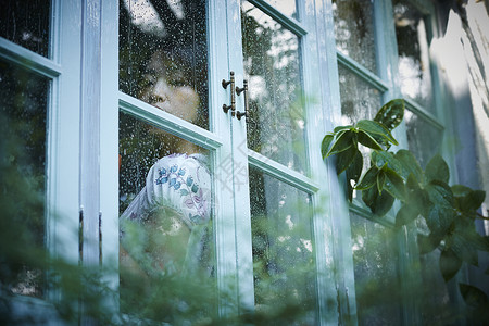 下雨天靠在窗边发呆的女性面部表情高清图片素材