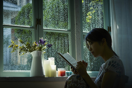 下雨天在窗边读书的孤独女性房间高清图片素材