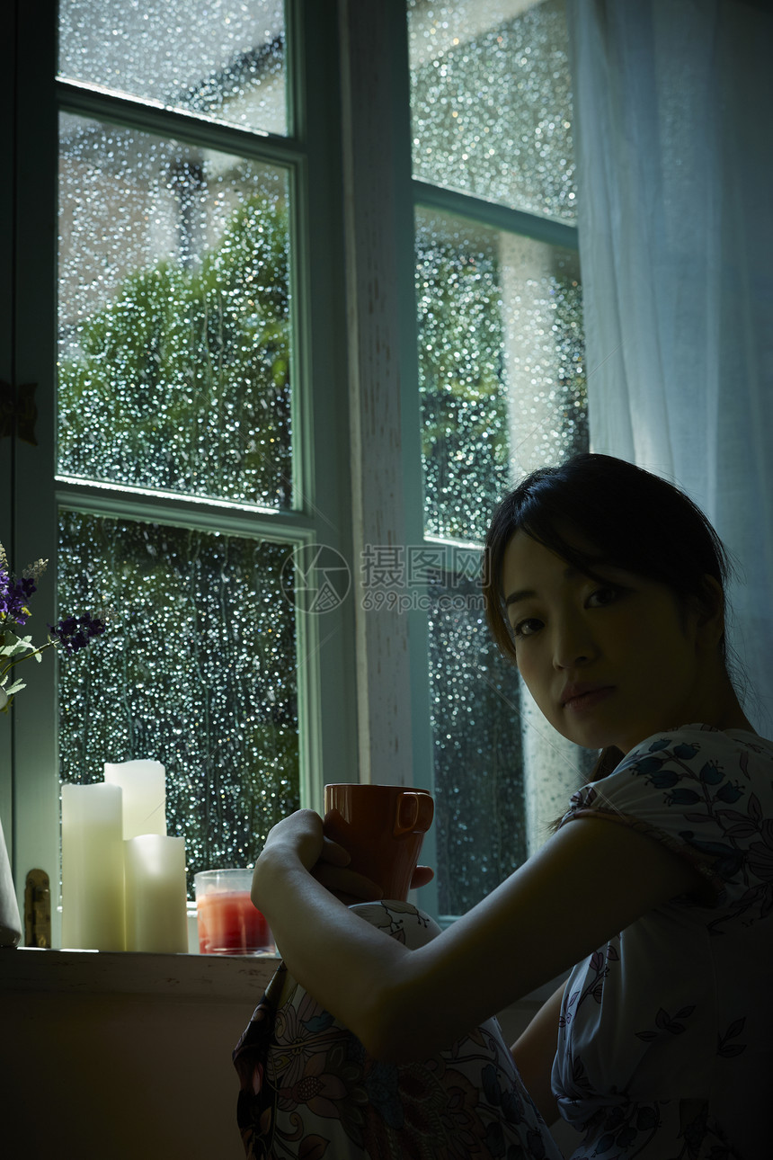 下雨天靠在窗边发呆的女性图片