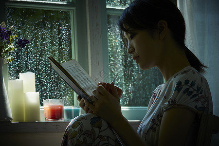 下雨天在窗边读书的孤独女性花瓶高清图片素材