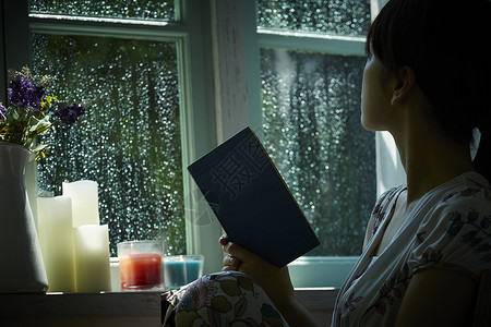 下雨天在窗边读书的孤独女性暴雨高清图片素材