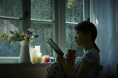 下雨天在窗边读书的孤独女性下午茶时间高清图片素材