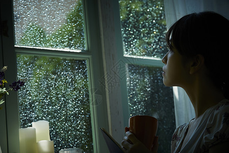 下雨天坐在窗边向外看的女生轻松高清图片素材