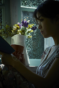 雨天在家看书喝茶的年轻女性青春高清图片素材