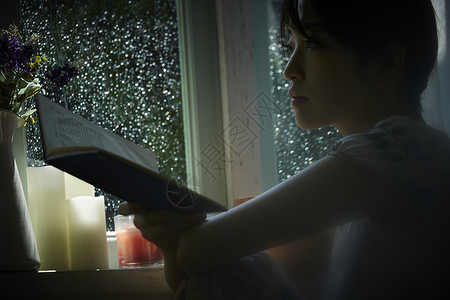 雨天在家看书放松的女青年客厅高清图片素材