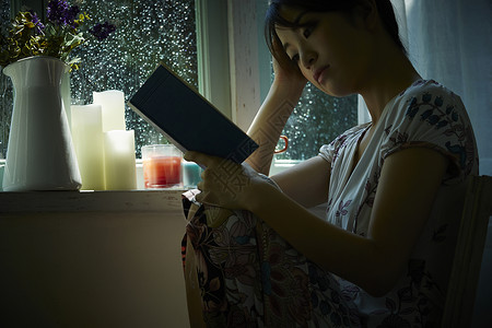 下雨天坐在窗边阅读休息的年轻女性花卉高清图片素材