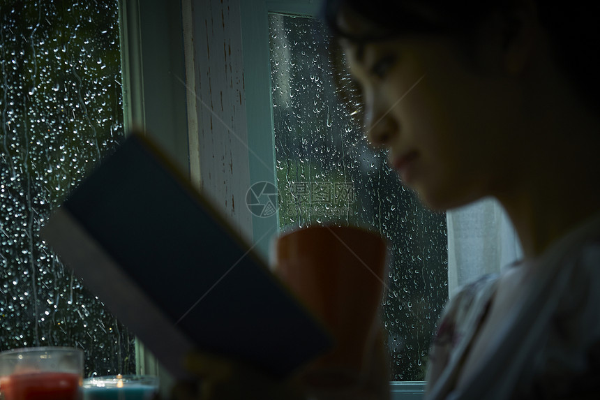 下雨天在家休息看书的女性图片
