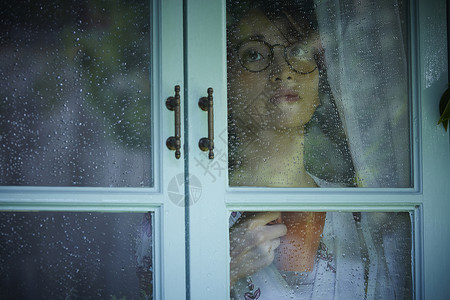 下雨天看向窗外的女青年图片