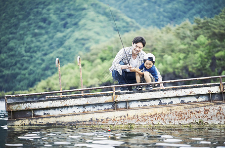 湖边码头享受钓鱼的父子图片