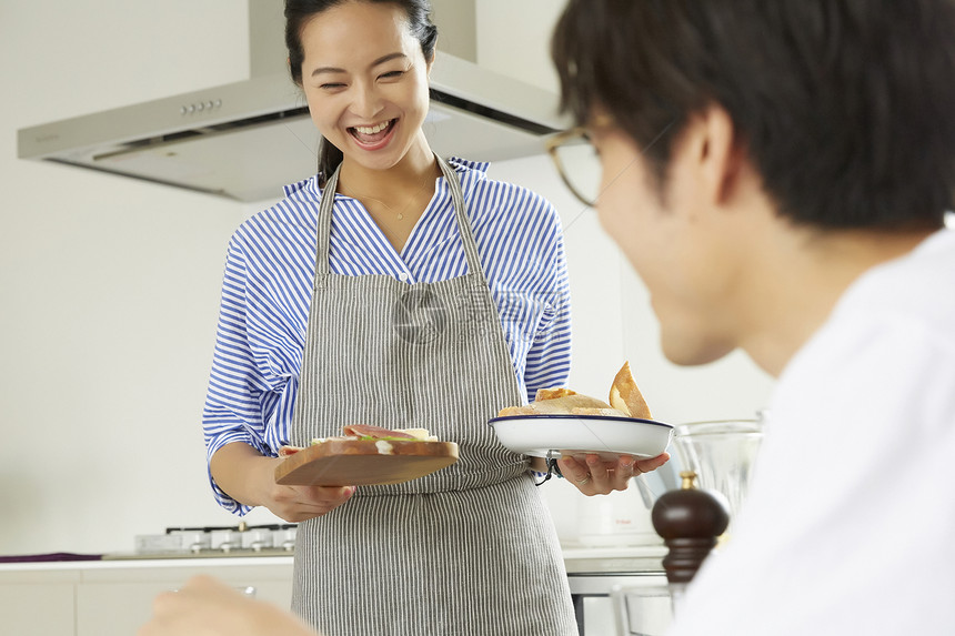 穿着围裙拿着餐盘微笑的家庭主妇图片