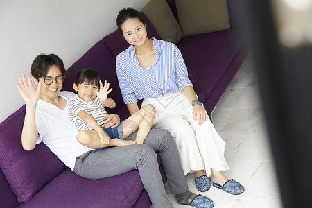 客厅沙发上开心招手的幸福一家人图片