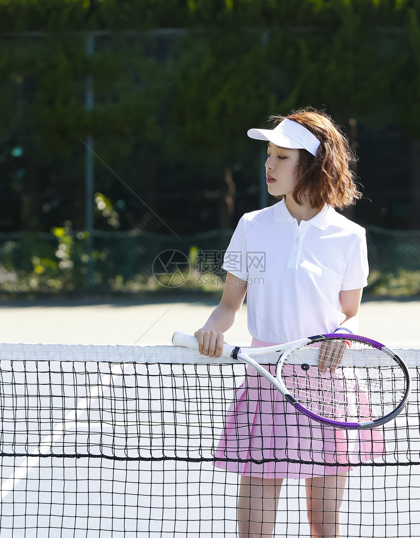 室外网球场拿着网球拍的女青年图片