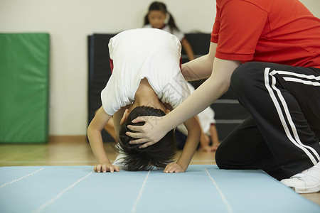 老师指导下在垫子上锻炼的小学生图片