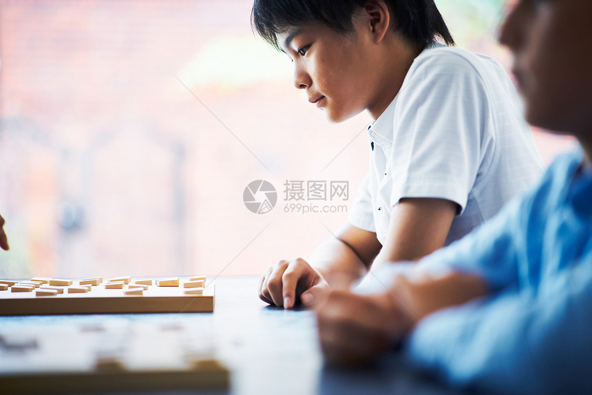 看着棋盘思考的小男孩图片