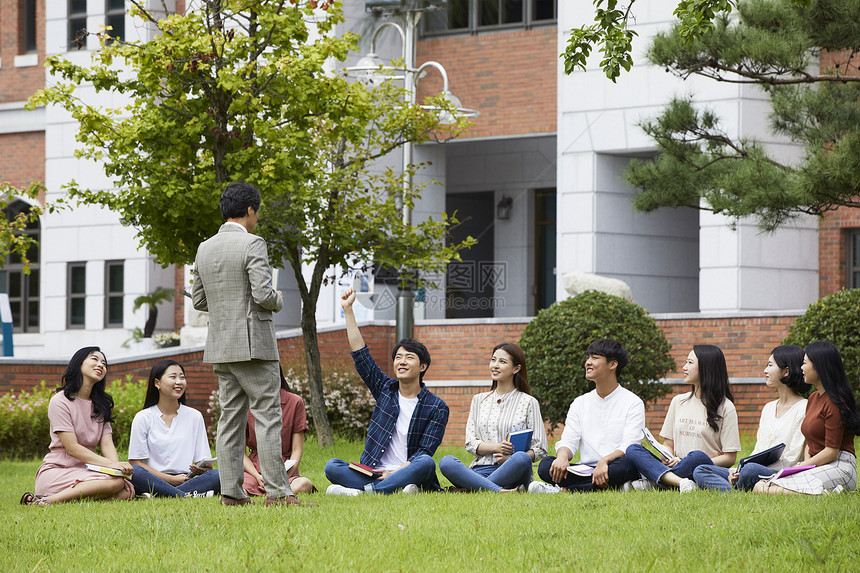 大学教授和学生们围坐在草地上分享交流图片