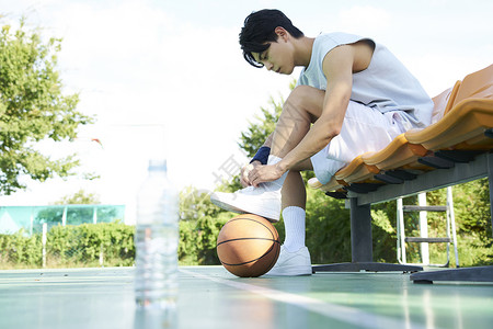 篮球场上的运动男青年系鞋带图片