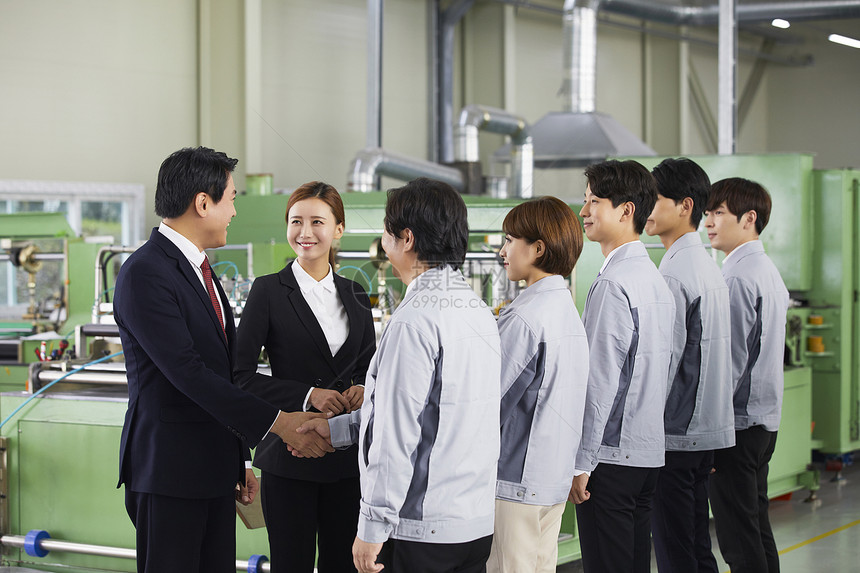 商务男士和工厂技术工人握手合作图片