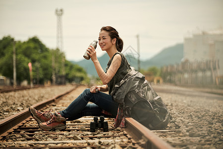 在废弃铁道上喝水的旅行者图片