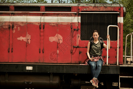 注视镜头女人背包在废弃火车前高清图片