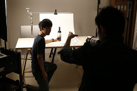摄影师正在教学员静物拍摄红葡萄酒高清图片素材