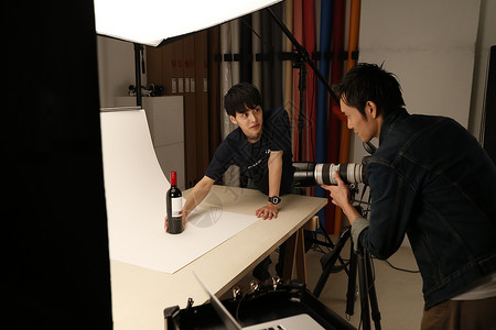 户内摄影师和助理拍摄红葡萄酒图片