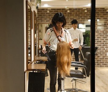 美发师的助理练习剪头发切断高清图片素材