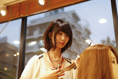 美发师的助理练习剪头发闭店高清图片素材