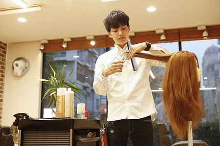 美发师的助理练习剪头发假发高清图片素材