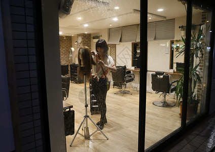 夜晚理发店内练习的美发师助理年轻人高清图片素材