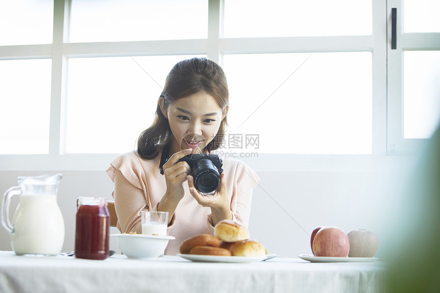 拿着数码相机拍食物照片女青年图片