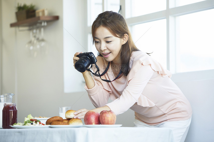 拿着数码相机摄影的年轻女性图片