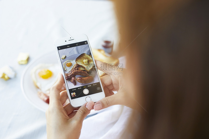 手机拍摄食物照片的女性图片