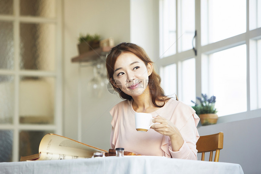 拿着咖啡杯享受下午茶的年轻女子图片